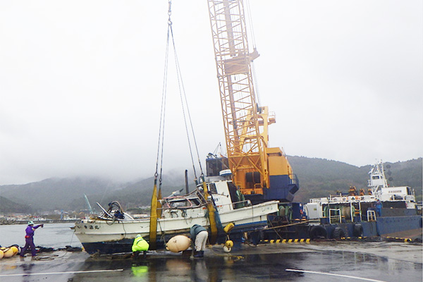 台風で沈没した漁船をクレーンで引き揚げる